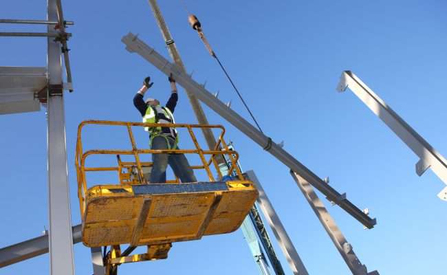 A construction worker using a scissor lift high up
