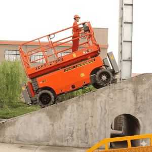 Dingli JCPT1218RT all-terrain scissor lift navigating a 40 percent incline on a construction site.